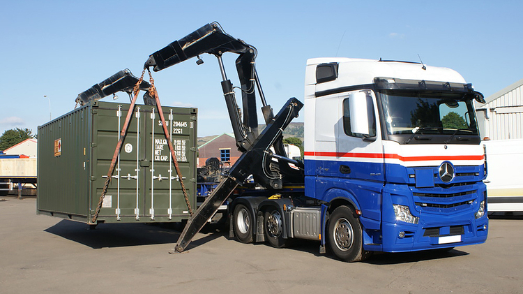 Vehicle container being lifted for secure car shipping by container transport